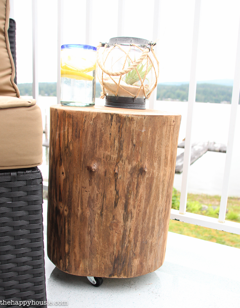 The DIY rolling stump with a glass and a nautical vase on the top of it.