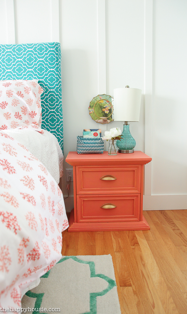 A bright coral nightstand beside the bed.