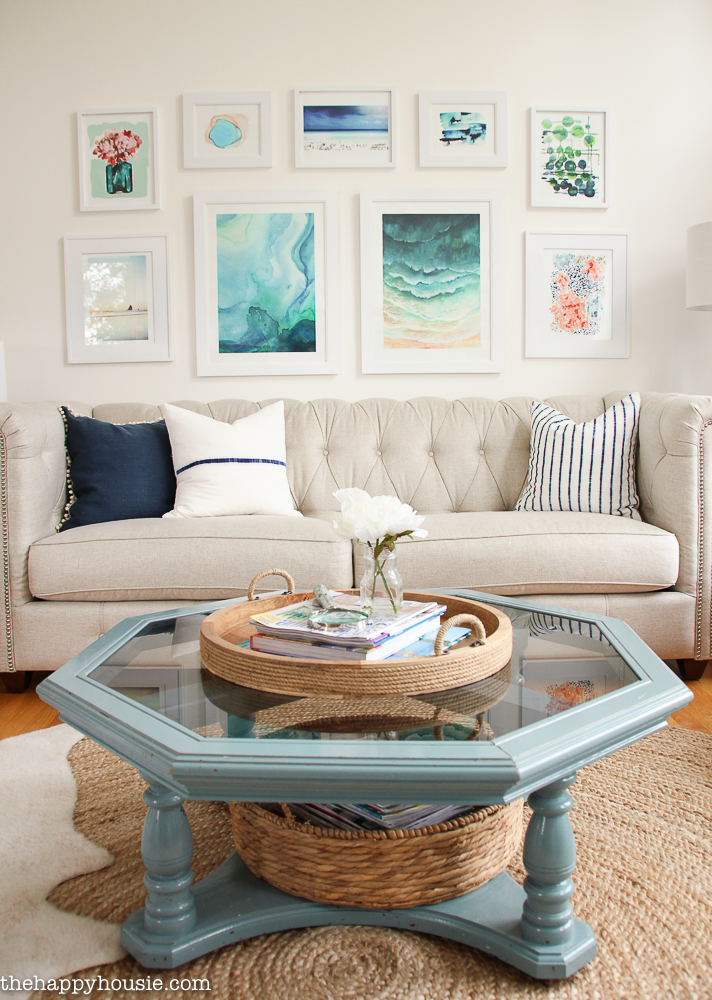 The coffee table in a light blue/grey with a tray in the middle holding a vase and books.