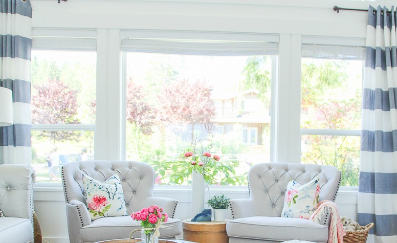 Two white armchairs in front of the living room window.