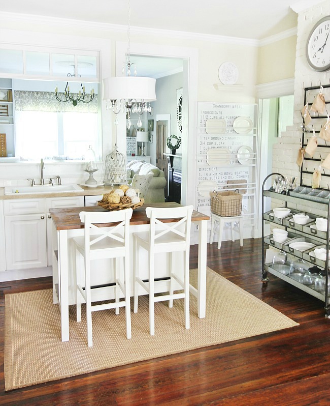 A mostly white kitchen with open shelving and a kitchen island with a butcher block top.