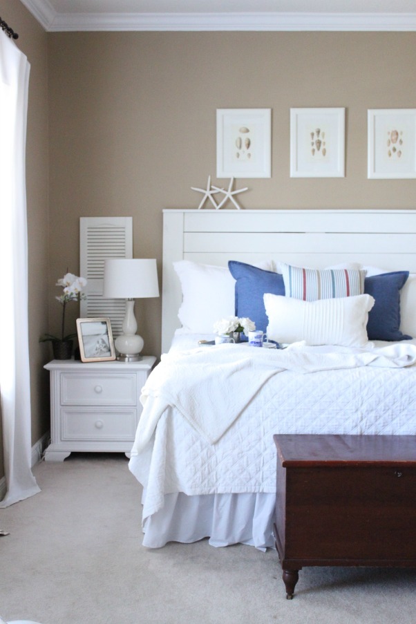 A white bed spread and headboard with starfish on it.