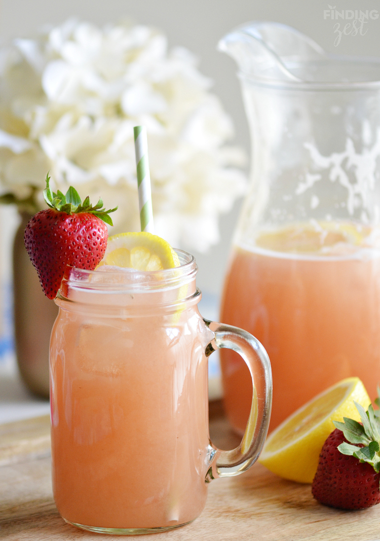  Homemade-Strawberry-Rhubarb-Lemonade in a mason jar with a handle and a pitcher beside it.