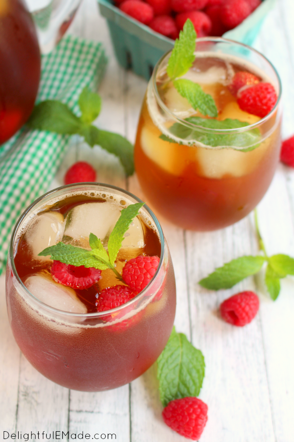 Raspberry mint tea in glasses with a raspberries beside it.