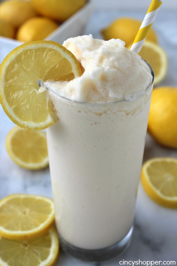 Sweet Summer Sips chick-fil-a-frosted-lemonade in a large glass with a lemon on the rim and cut lemons around it.
