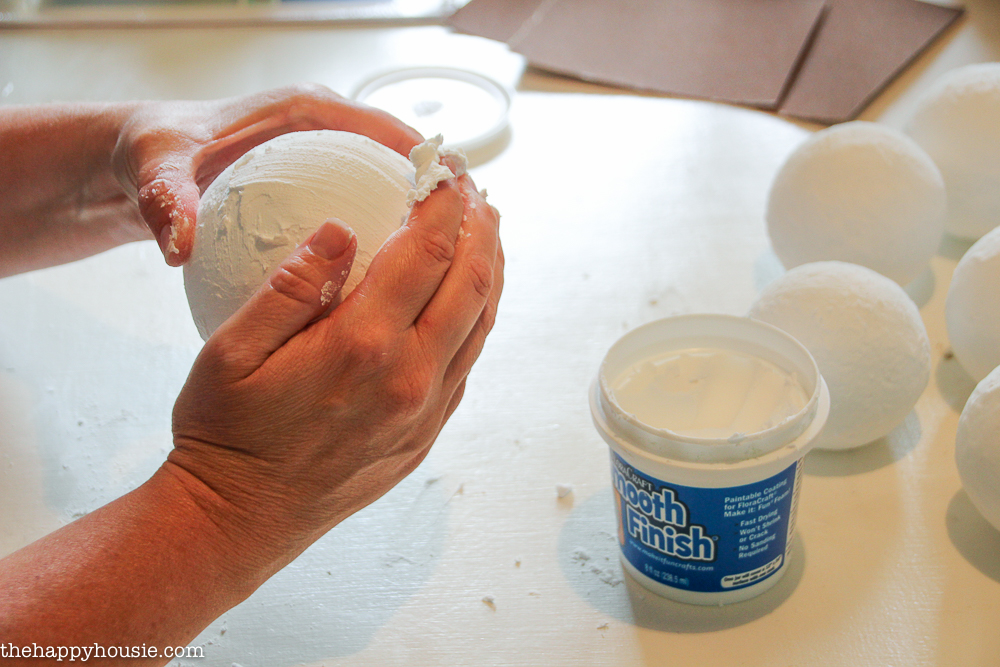Rubbing smooth finish onto the styrofoam balls.