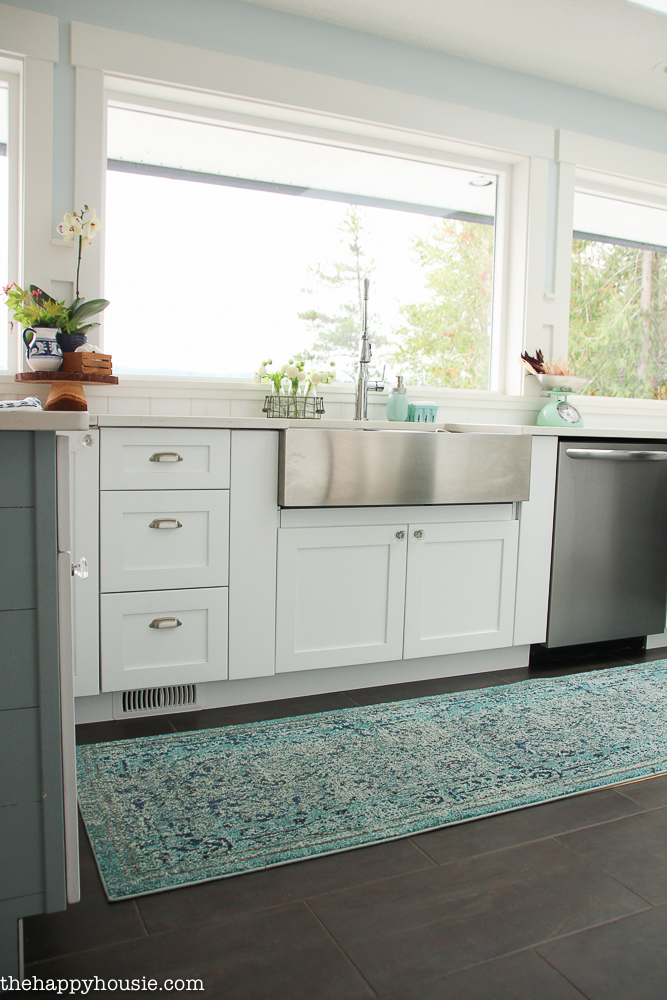 A runner rug in front of a kitchen sink on the floor.