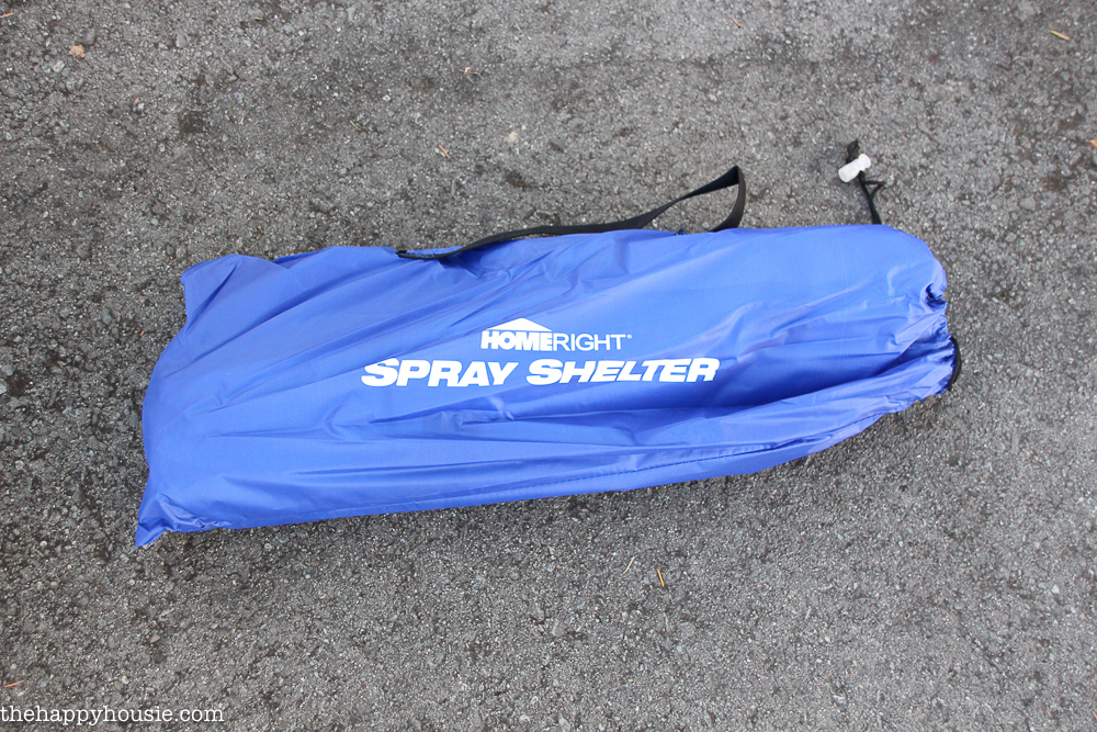 A spray shelter in its carrying case on the ground.