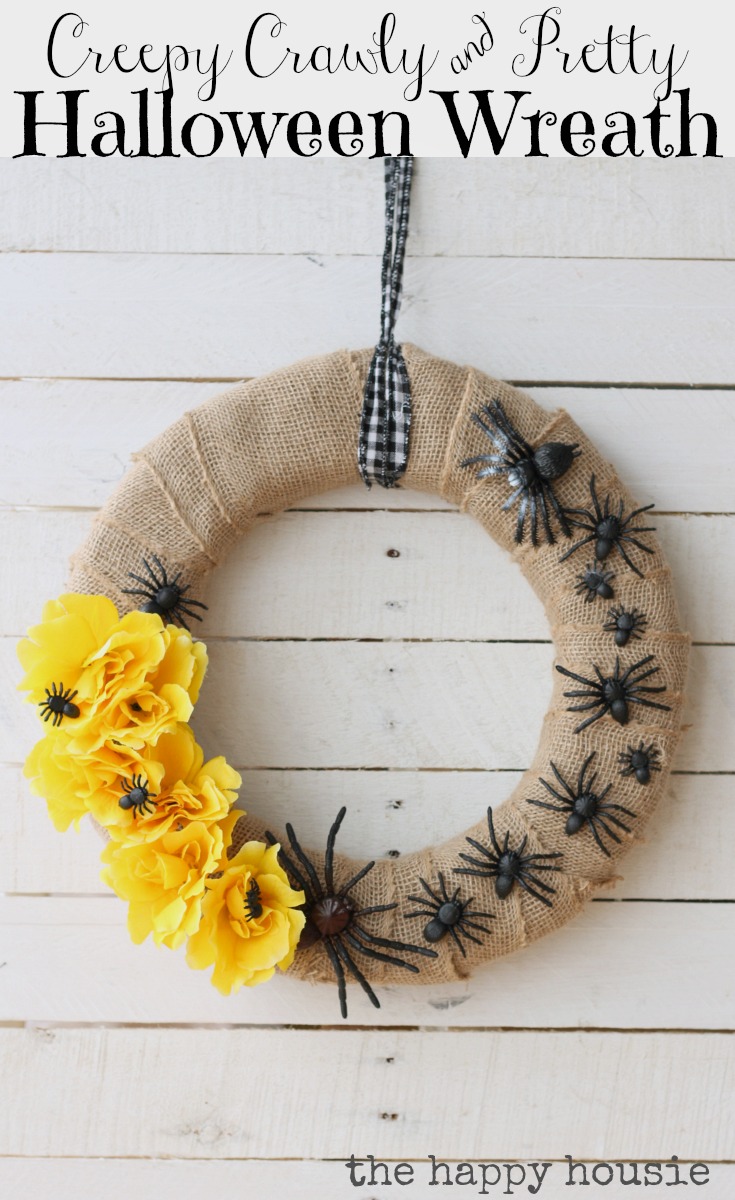 A burlap wrapped wreath with black plastic spiders and yellow flowers.