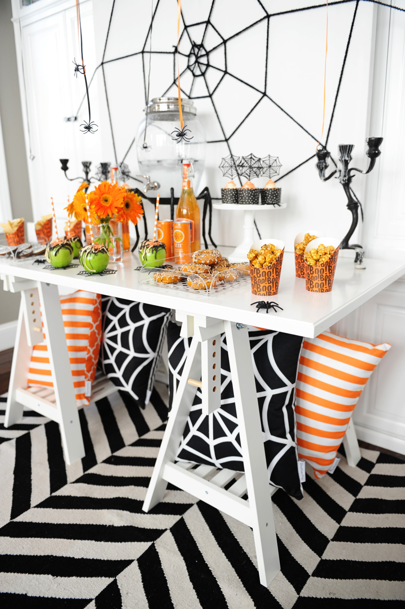 Halloween party decor with a white table filled with spooky items.