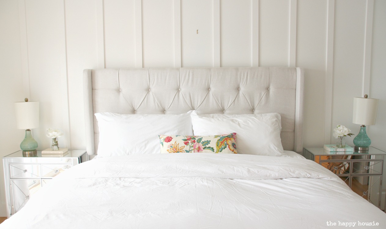 A white bed with a white upholstered headboard.