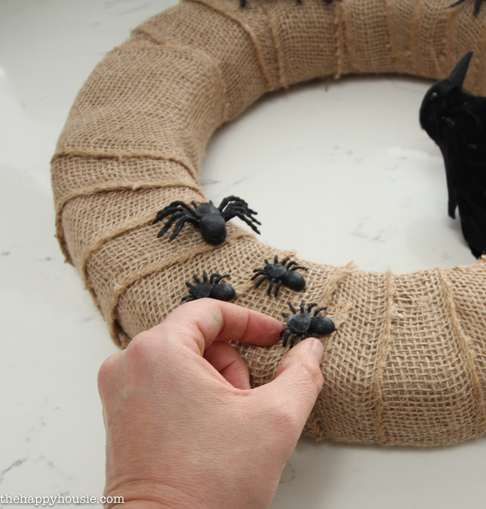 Putting black spiders along the burlap wrapped wreath.