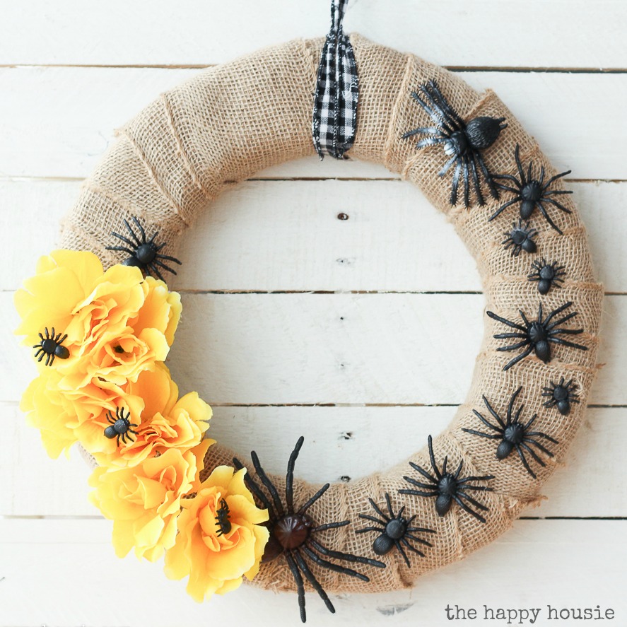 A wreath with black spiders and yellow flowers.