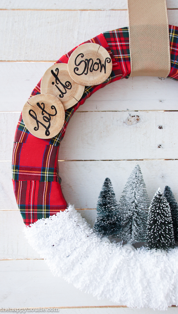 Up close of the let it snow in wood on the wreath.