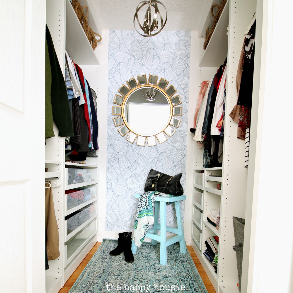 A large walk in closet with a round mirror on the wall.