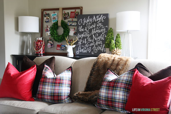 Plaid and red throw pillows on a neutral couch.