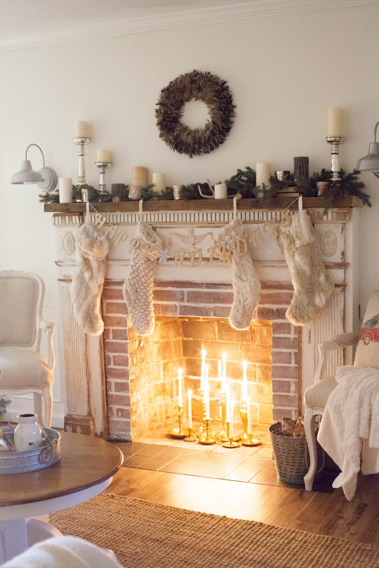 Lit candles are in the fireplace with a stockings and a wreath above the mantel.