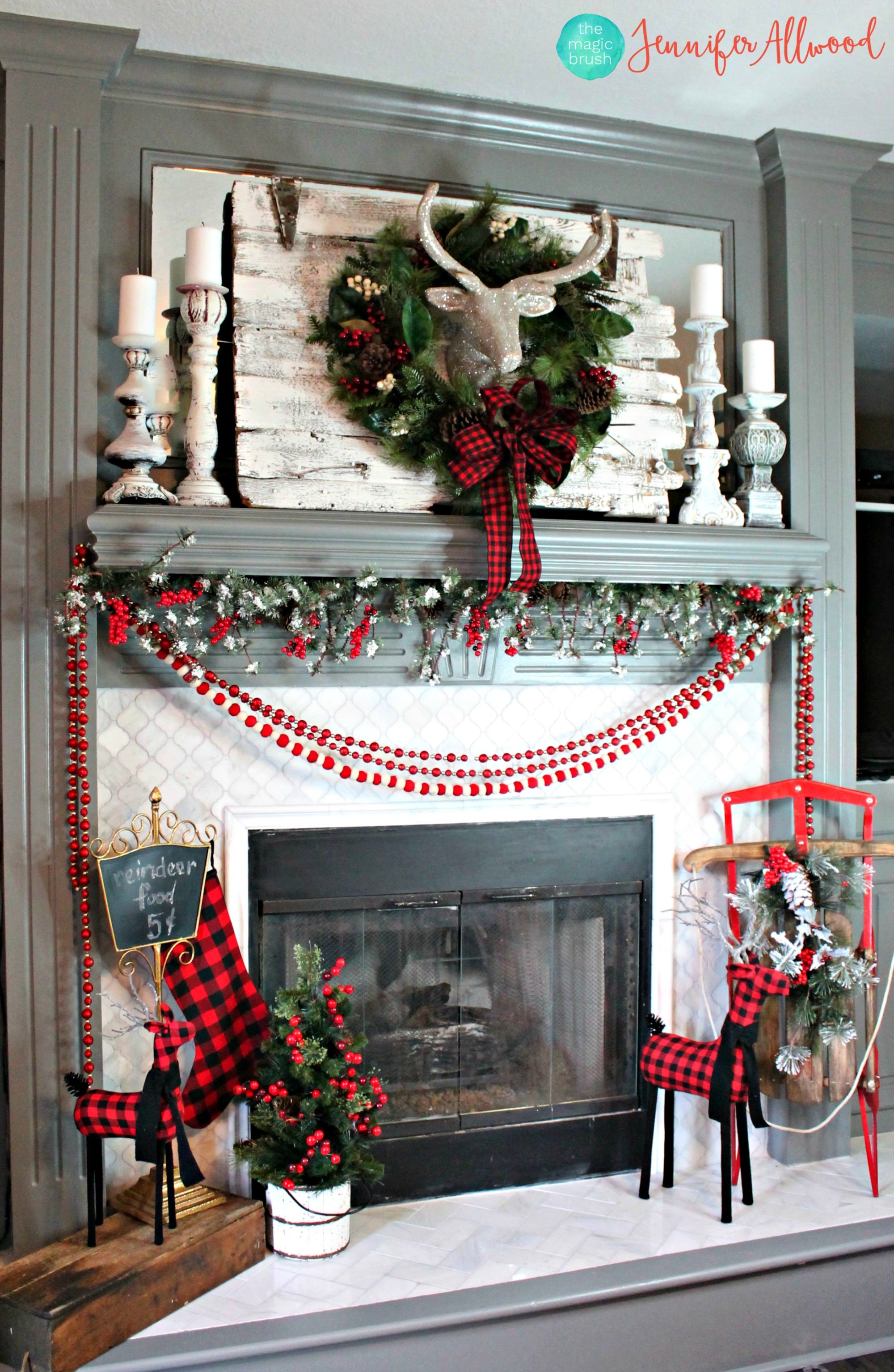 A fireplace with red garland and a large wreath above it.