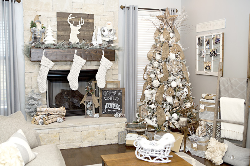 A white fireplace with a deer antler picture and white stockings.