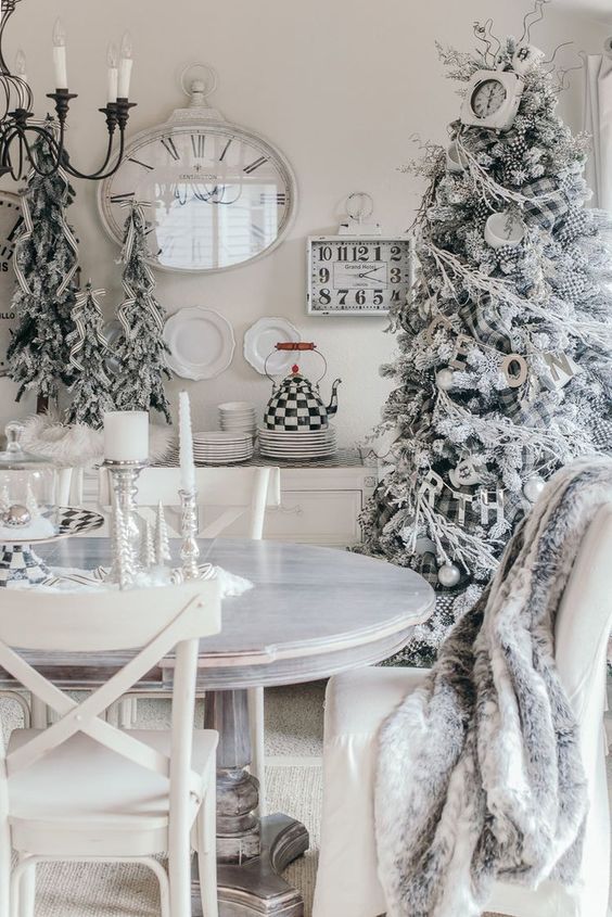 A flocked White Christmas tree in the dining room with a white table and decor.