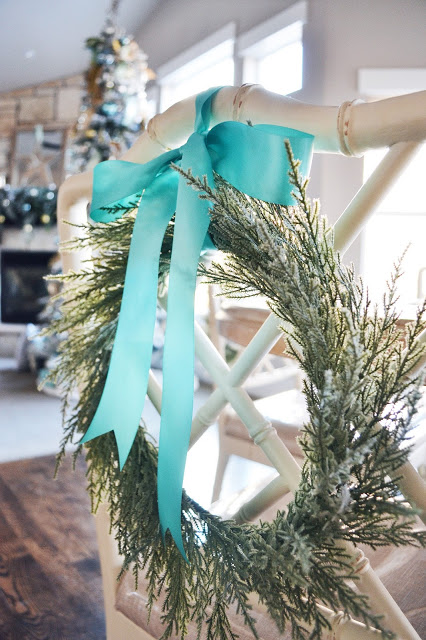 A simple wreath on a chair with a blue ribbon.