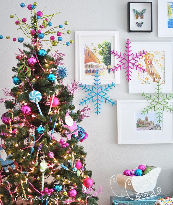 A very colourful decorated Christmas tree with pink and blue snowflakes.