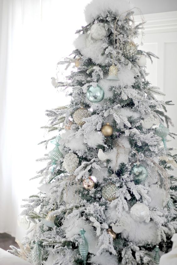 A mostly White Christmas tree with soft blue and green ornaments.