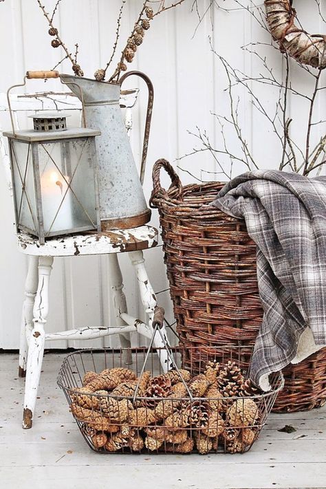 A wire basket is filled with pine cones and a basket with a plaid blanket inside it.