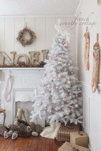 A rustic White Christmas tree in front of a vintage fireplace mantel.