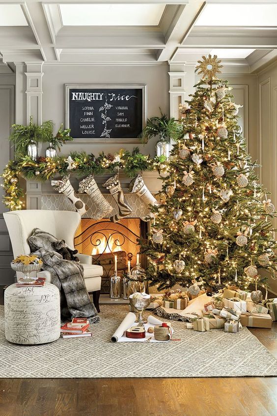 A fireplace mantle with stockings hanging up and a large tree beside it.
