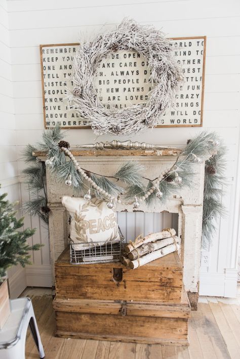 A rustic wooden fireplace mantel with a white wreath above it.