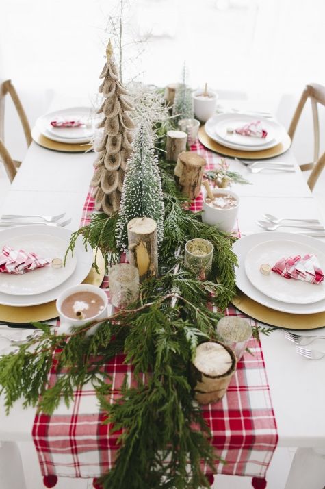 A table runner that is red plaid with evergreen and candles.