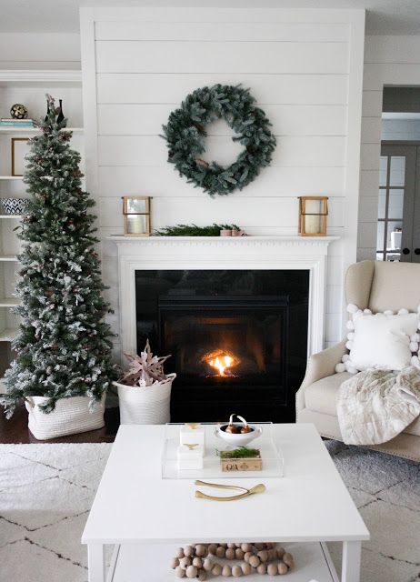 A fireplace that is on with a green wreath above it.