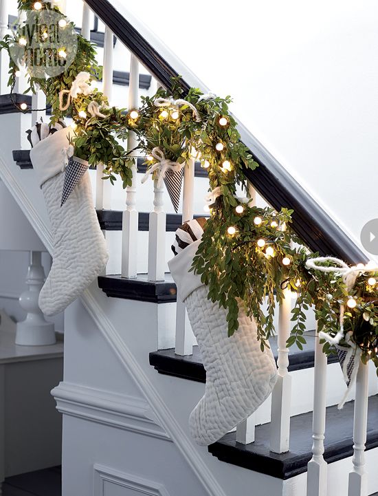 A stairway with white stocking and greenery as garland on the railing.