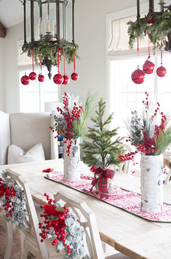 A white table and chairs with evergreen and red berries and red ribbon.