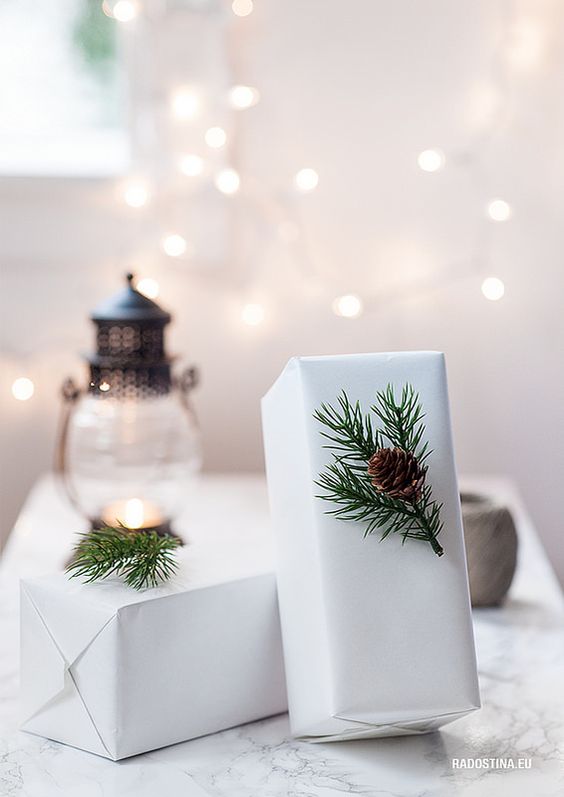 Presents wrapped in white paper with a sprig of evergreen and a pine cone.