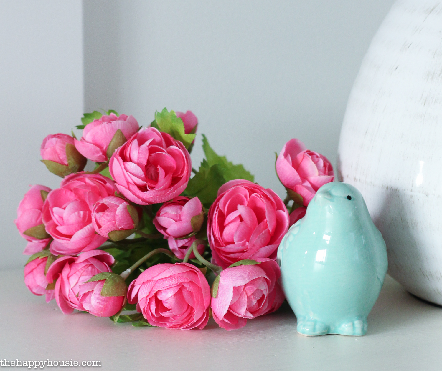 Up close picture of pink flowers and a blue ceramic bird.