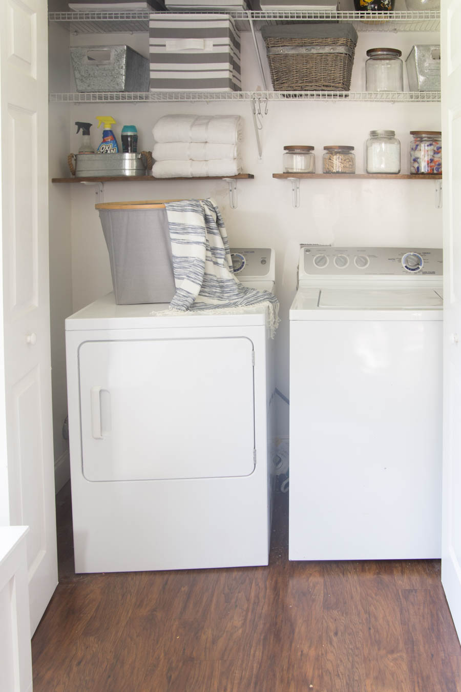 There is a washer and dryer tucked away in a closet with shelves.