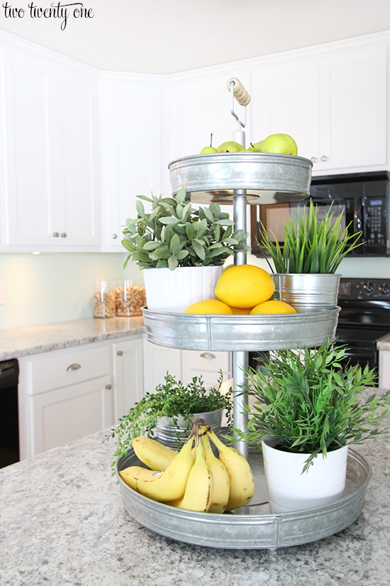 A galvanized tiered tray with bananas and plants.
