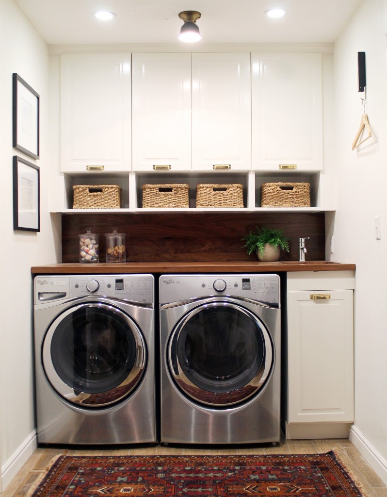 A decorative rug is in front of the washer and dryer.
