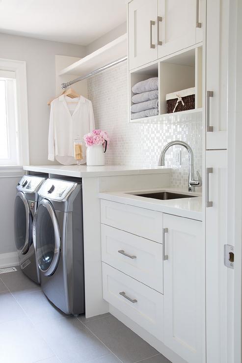 A tiled backsplash is in this small laundry room.