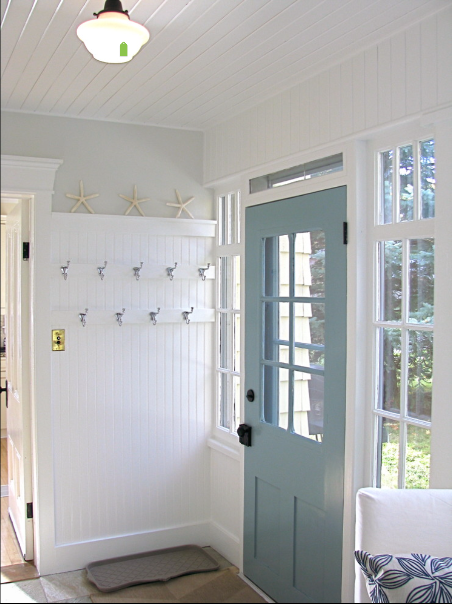 White shiplap wall with hooks and starfish by the blue door.