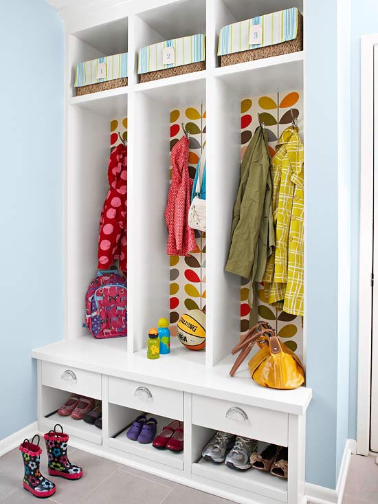 A white closet with wallpaper behind it and jackets on hooks.