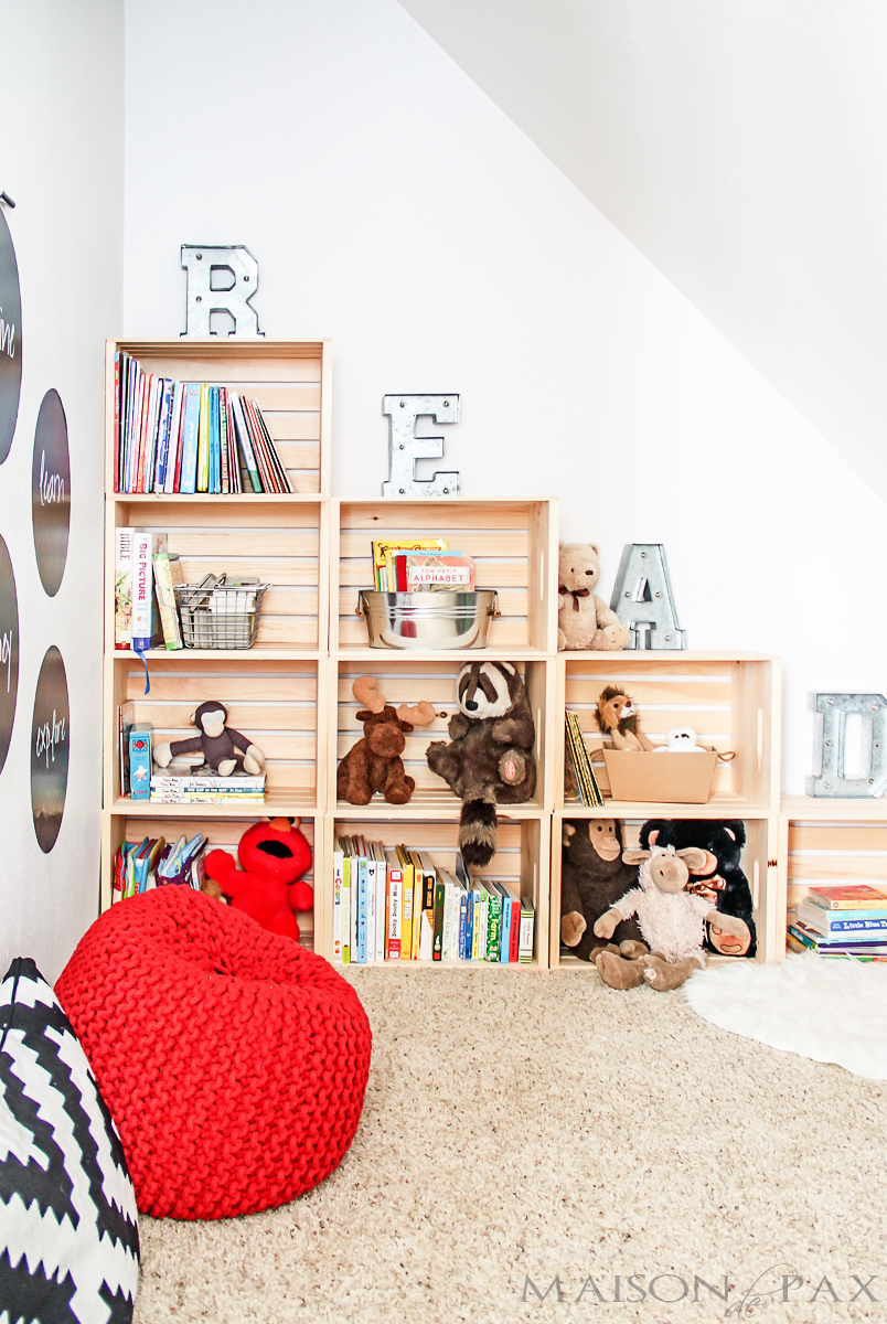 A large wooden crate bookshelf with stuffed animals and books on it.