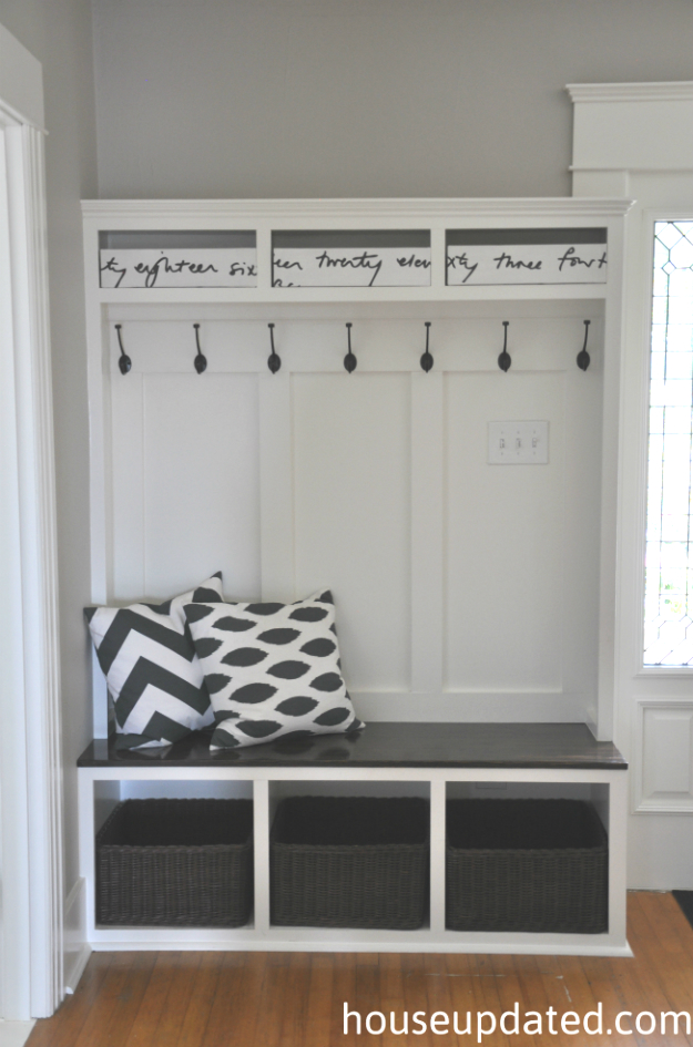 White entryway hall mud room with black bench, cushions and hooks.