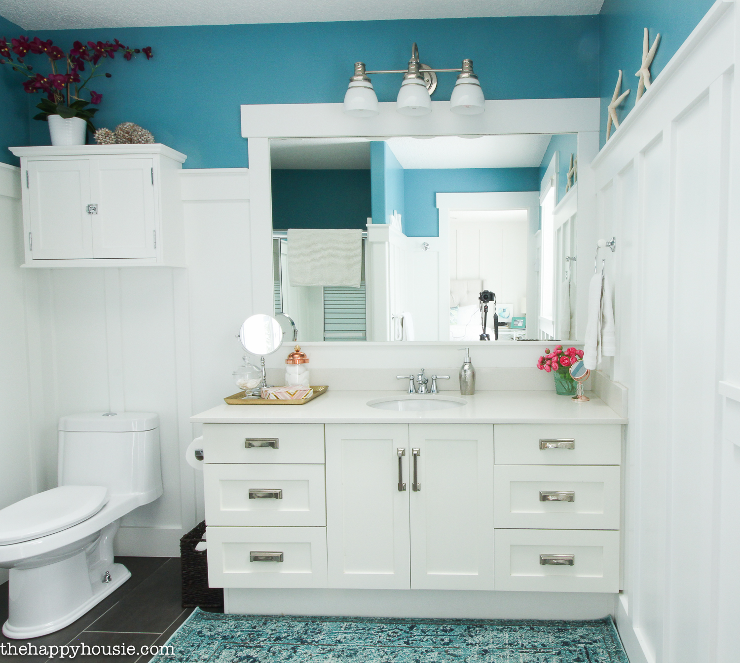 Blue bathroom walls with white cabinets.
