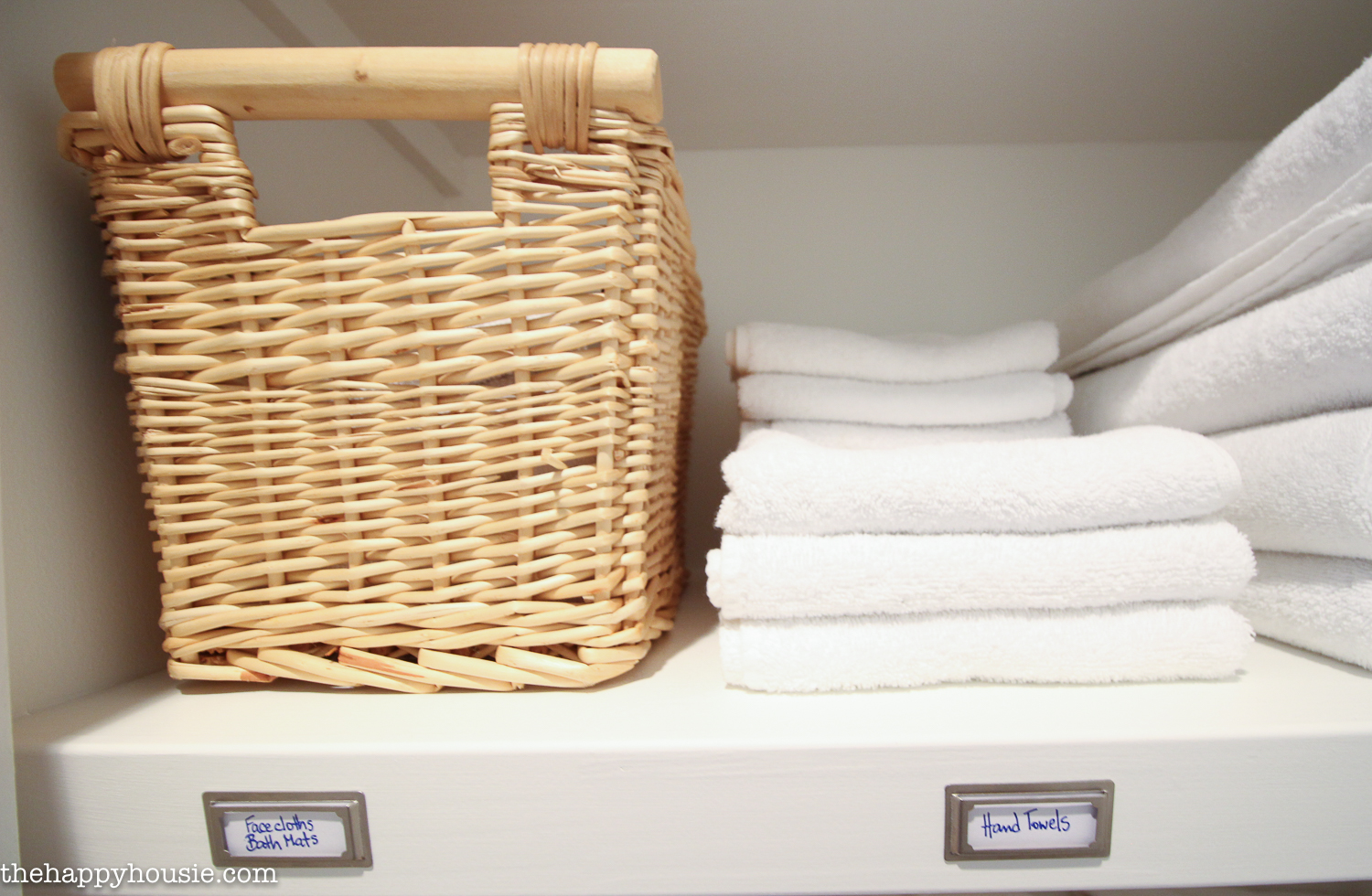 A wicker basket on the shelf and hand towels beside it.