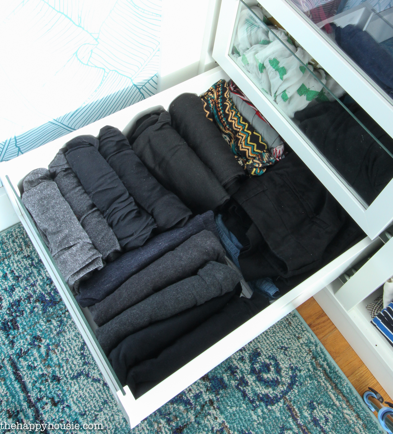A drawer filled with rolled up clothing items.