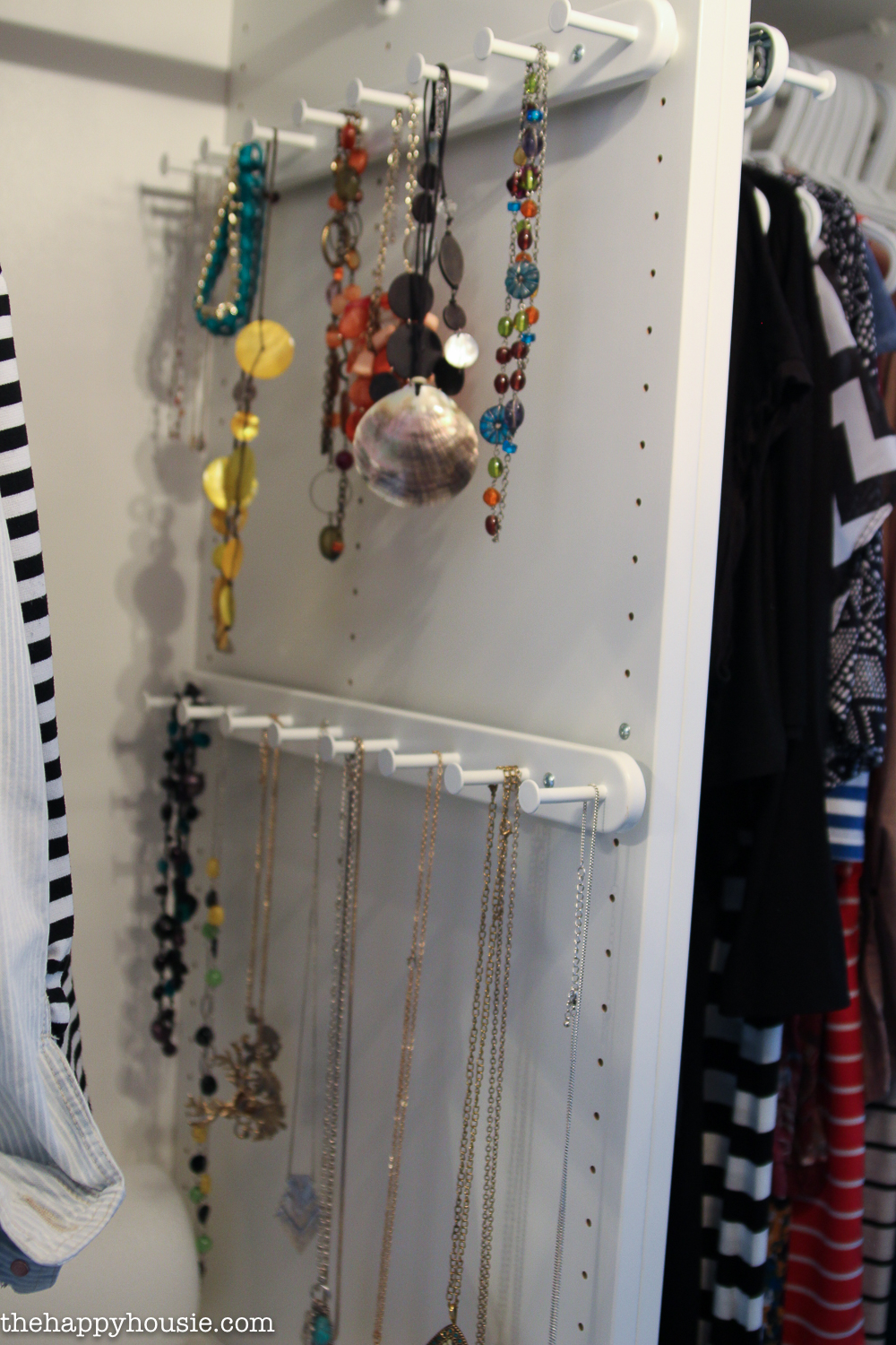 Jewellery hanging from pegs in the closet.