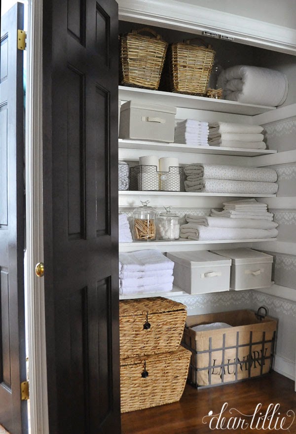 A wooden door to the closet with wire and wicker baskets and white towels.
